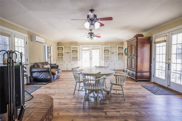 dining space featuring a textured ceiling, a wall mounted AC, wood-type flooring, and french doors