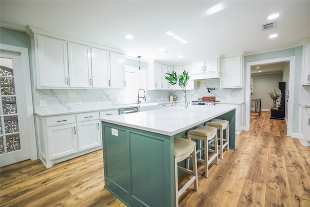 kitchen with a breakfast bar area, pendant lighting, light hardwood / wood-style flooring, and white cabinets