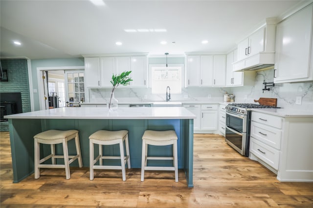 kitchen featuring a center island, double oven range, sink, light wood-type flooring, and white cabinets