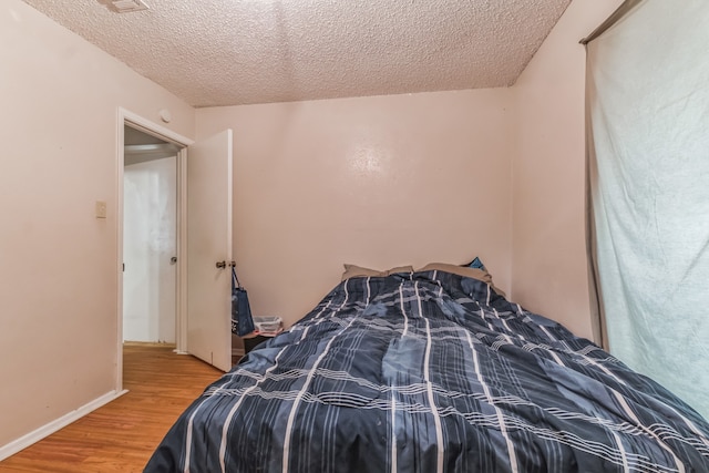 bedroom featuring a textured ceiling and hardwood / wood-style flooring