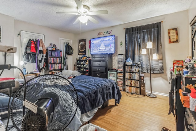 bedroom with a ceiling fan, a textured ceiling, baseboards, and wood finished floors