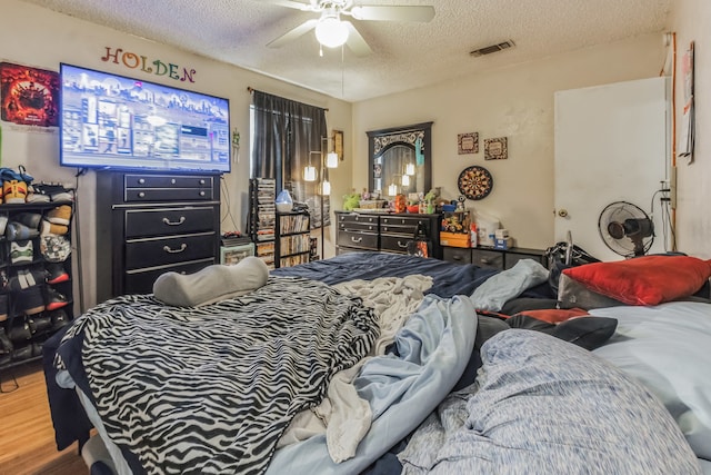 bedroom with a textured ceiling, ceiling fan, and wood-type flooring