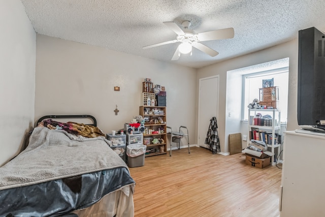 bedroom featuring ceiling fan, a textured ceiling, and light hardwood / wood-style flooring