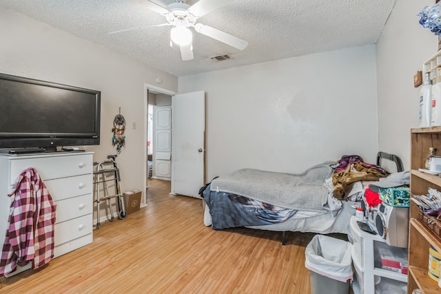 bedroom with a textured ceiling, light wood-type flooring, and ceiling fan