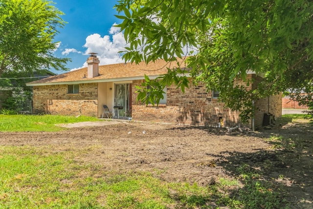 rear view of property with brick siding and a chimney