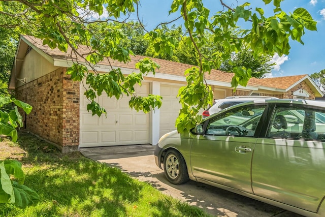 exterior space with a garage, driveway, brick siding, and a shingled roof