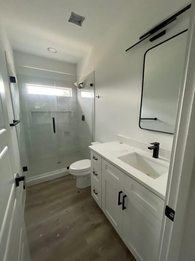 bathroom featuring wood-type flooring, toilet, vanity, and an enclosed shower