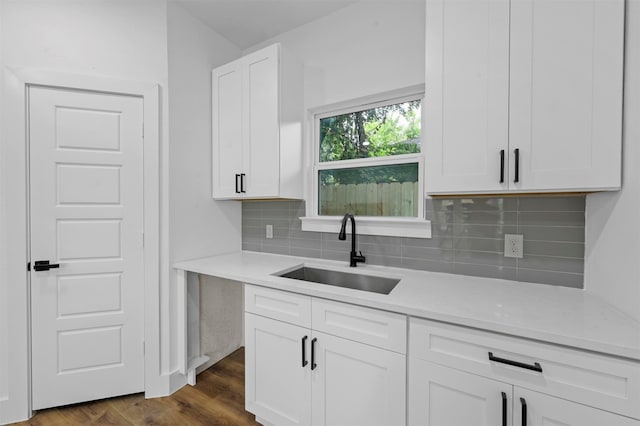 kitchen featuring white cabinets, decorative backsplash, sink, light stone counters, and dark hardwood / wood-style floors