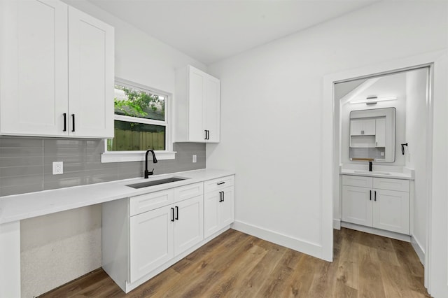 kitchen with sink, white cabinetry, decorative backsplash, and light wood-type flooring