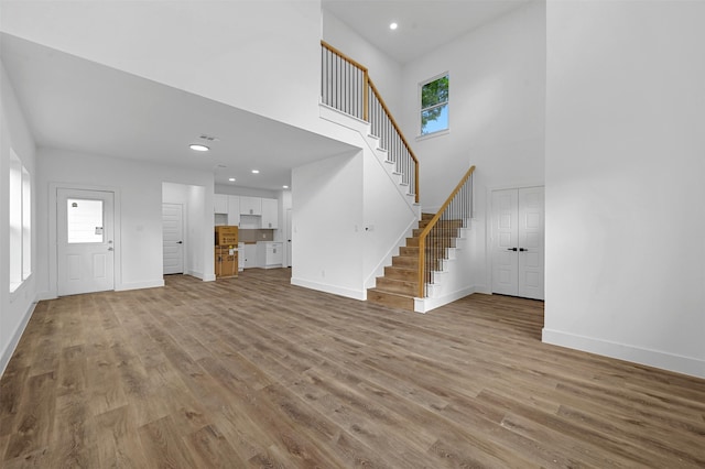 unfurnished living room featuring light hardwood / wood-style flooring, a wealth of natural light, and a towering ceiling