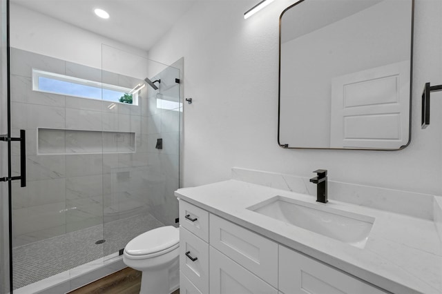 bathroom with hardwood / wood-style flooring, toilet, vanity, and an enclosed shower