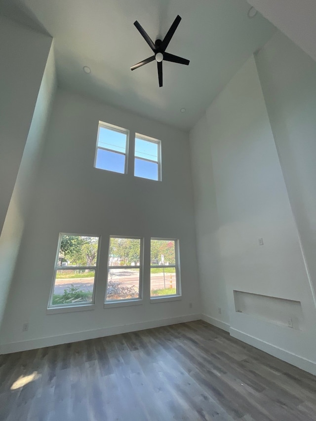 additional living space with a high ceiling, ceiling fan, and wood-type flooring