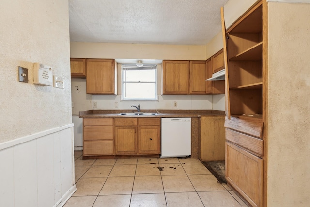 kitchen with dishwasher, wood walls, a textured ceiling, sink, and light tile patterned flooring