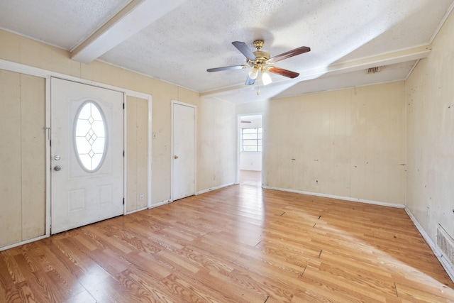 foyer entrance with a textured ceiling, ceiling fan, light hardwood / wood-style floors, and beam ceiling