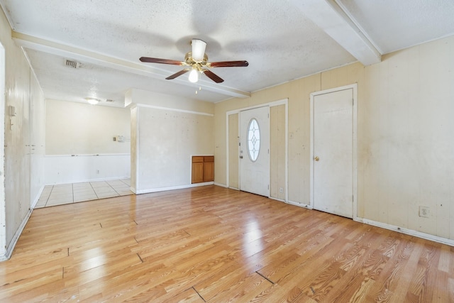 foyer with beam ceiling, ceiling fan, light wood-type flooring, and a textured ceiling