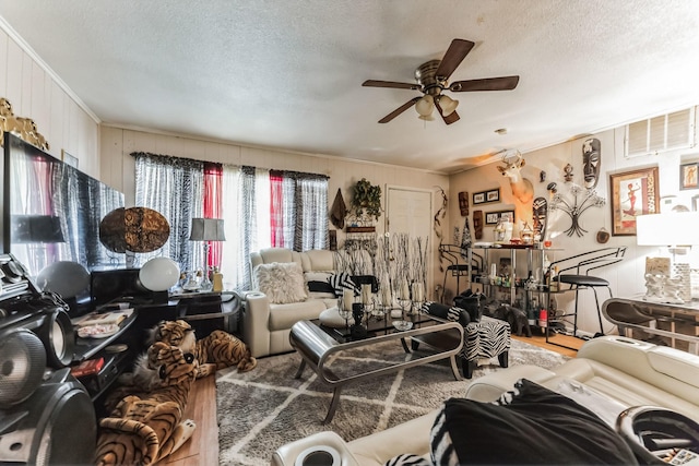 living room with a textured ceiling, ceiling fan, and crown molding