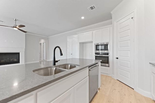 kitchen with white cabinetry, sink, dark stone counters, appliances with stainless steel finishes, and ornamental molding