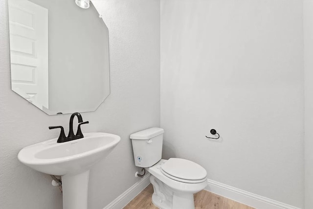 bathroom with wood-type flooring, toilet, and sink