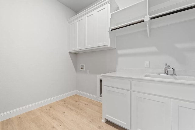 laundry area with cabinets, hookup for a washing machine, light hardwood / wood-style flooring, and sink