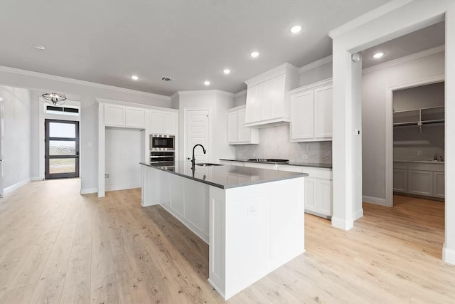 kitchen with a center island with sink, white cabinetry, sink, and stainless steel appliances