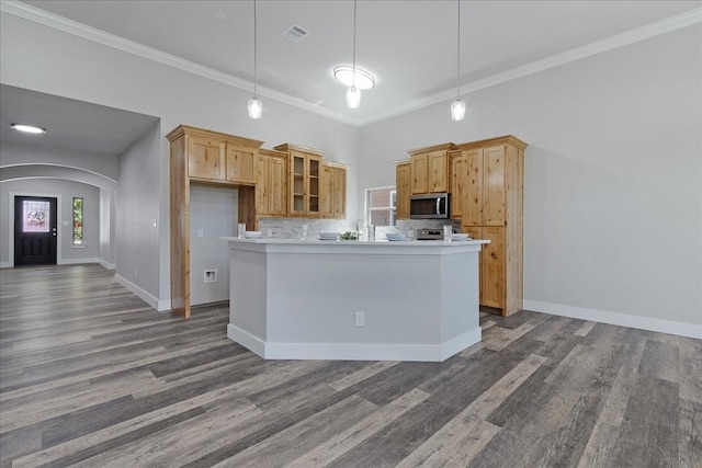 kitchen featuring tasteful backsplash, hanging light fixtures, light brown cabinetry, wood-type flooring, and ornamental molding