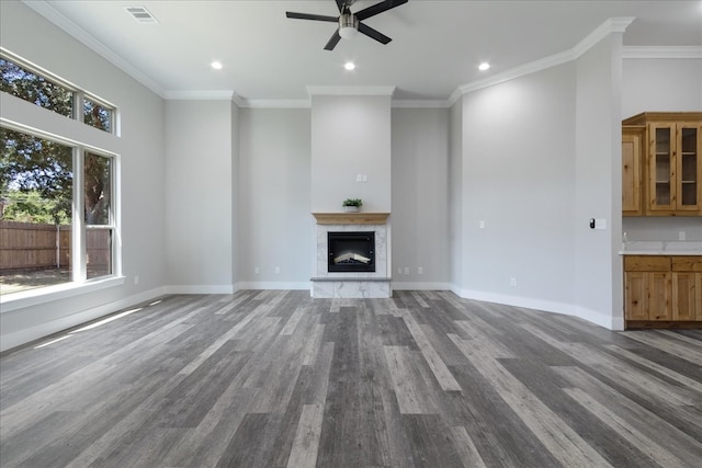 unfurnished living room with a high end fireplace, crown molding, dark hardwood / wood-style floors, and ceiling fan