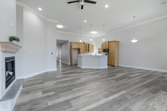 unfurnished living room with a premium fireplace, light hardwood / wood-style flooring, ceiling fan, and ornamental molding