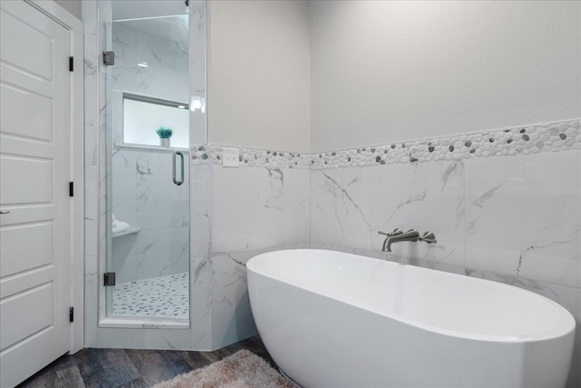 bathroom with shower with separate bathtub, hardwood / wood-style flooring, and tile walls