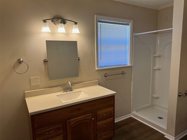 bathroom featuring walk in shower, vanity, crown molding, and hardwood / wood-style flooring