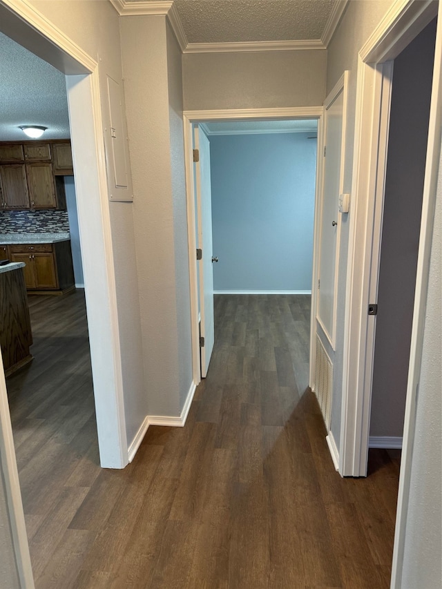 hallway featuring dark hardwood / wood-style floors, a textured ceiling, and ornamental molding