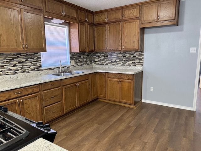 kitchen with dark hardwood / wood-style floors, backsplash, light stone counters, and sink