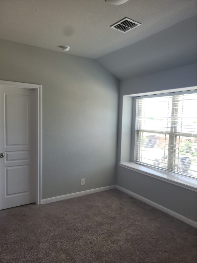 unfurnished room featuring dark colored carpet and lofted ceiling