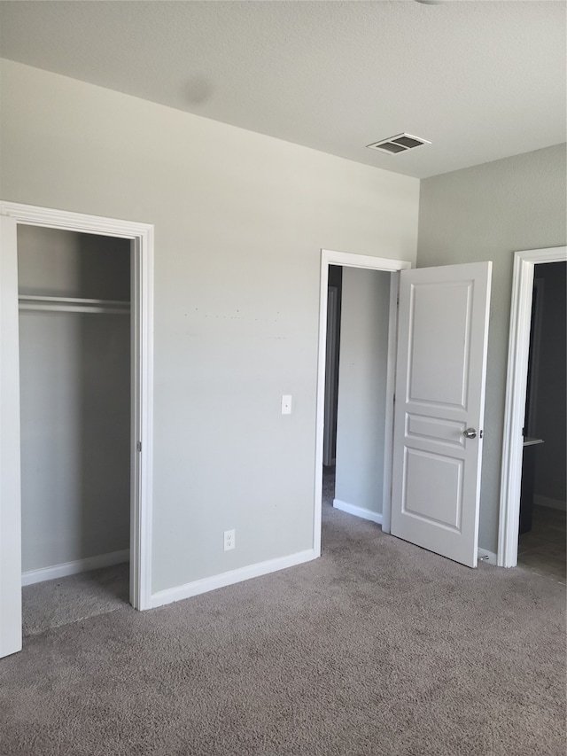 unfurnished bedroom with dark colored carpet and a closet