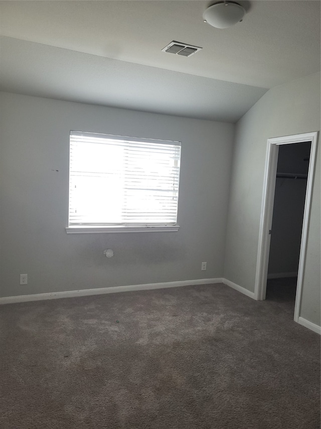 carpeted empty room featuring vaulted ceiling