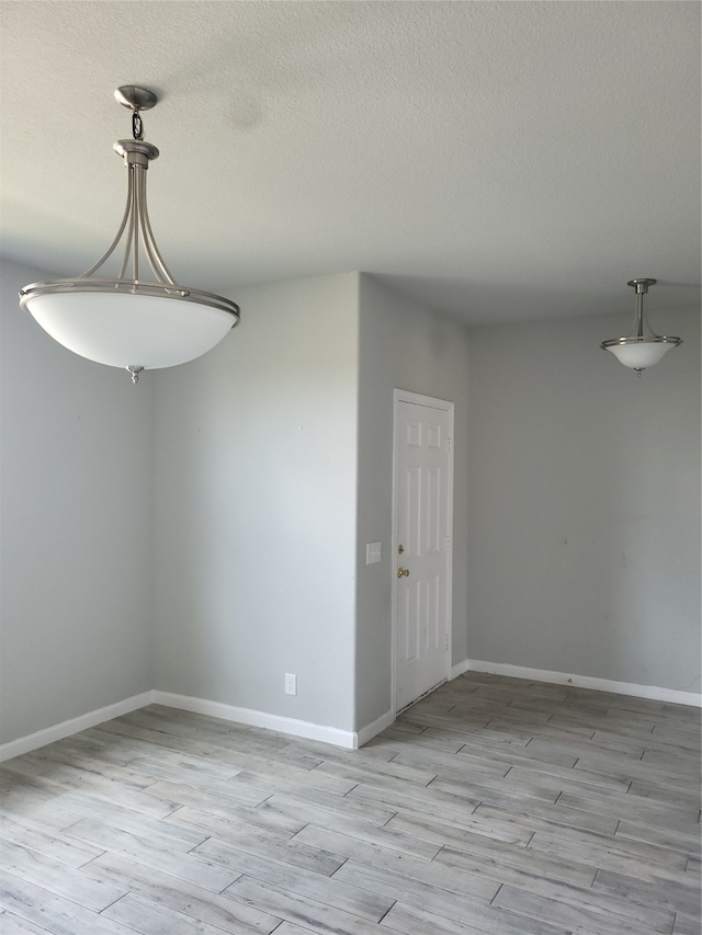 empty room featuring a textured ceiling and light hardwood / wood-style floors