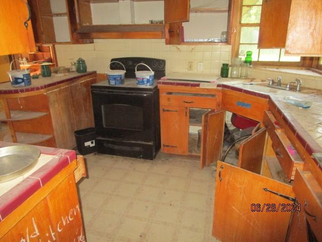 kitchen with tile counters, tasteful backsplash, and black electric range