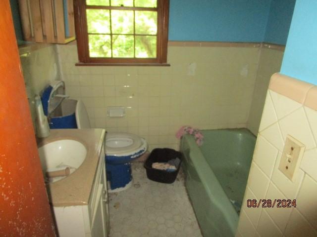 bathroom featuring vanity, toilet, tile walls, and a bathing tub