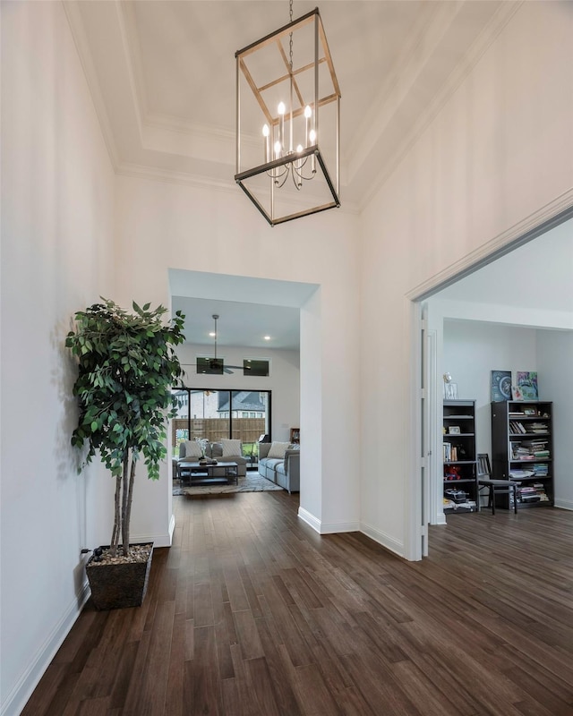 foyer entrance featuring dark hardwood / wood-style flooring, an inviting chandelier, and ornamental molding