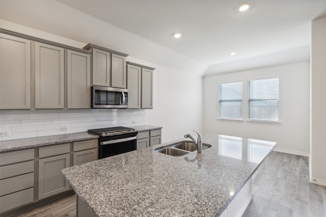 kitchen with sink, a center island with sink, backsplash, and stainless steel appliances