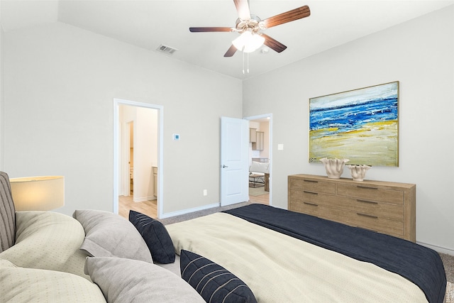 bedroom featuring ceiling fan, lofted ceiling, light colored carpet, and ensuite bath