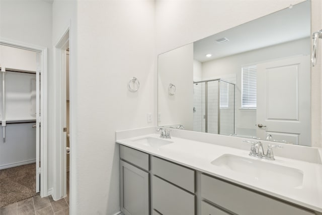 bathroom with tile patterned flooring, dual bowl vanity, and walk in shower