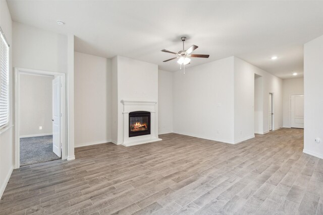 unfurnished living room featuring light colored carpet and ceiling fan