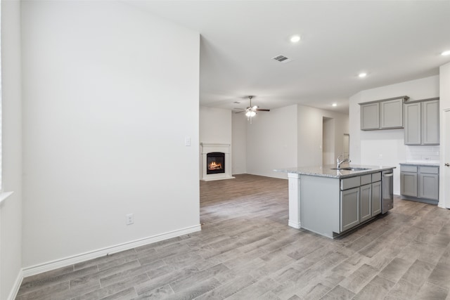 kitchen with light wood-type flooring, backsplash, sink, and gray cabinets