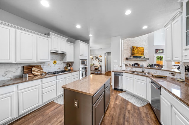 kitchen featuring sink, appliances with stainless steel finishes, dark hardwood / wood-style flooring, dark stone counters, and white cabinets