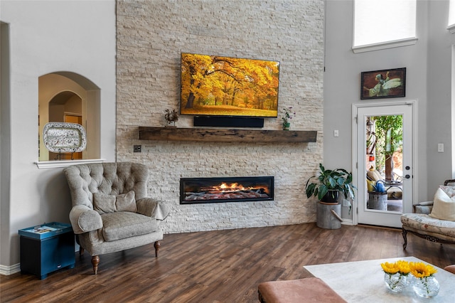 living room with dark wood-type flooring, a fireplace, and a high ceiling