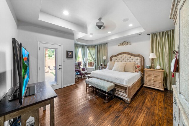 bedroom with access to exterior, a tray ceiling, dark hardwood / wood-style floors, and ceiling fan