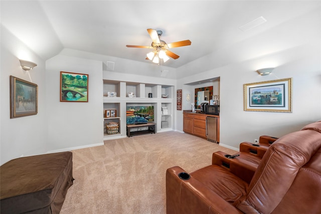 carpeted living room with lofted ceiling, ceiling fan, and built in shelves