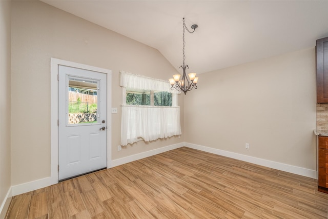 unfurnished dining area with an inviting chandelier, lofted ceiling, and light hardwood / wood-style flooring