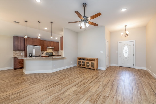 kitchen featuring stainless steel appliances, light hardwood / wood-style floors, decorative backsplash, decorative light fixtures, and kitchen peninsula