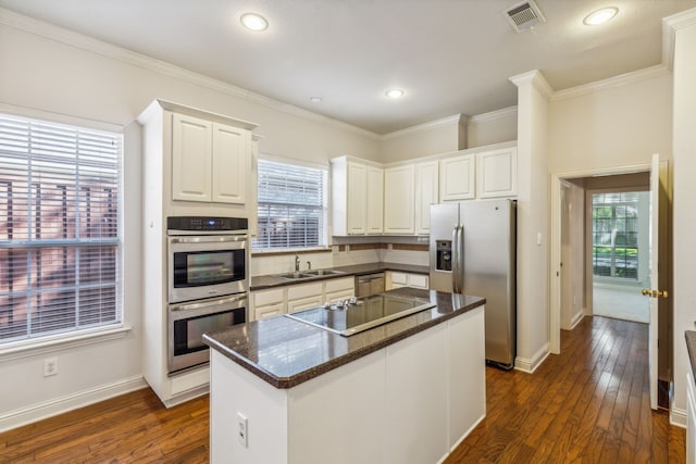 kitchen featuring appliances with stainless steel finishes, a kitchen island, dark hardwood / wood-style floors, white cabinetry, and plenty of natural light